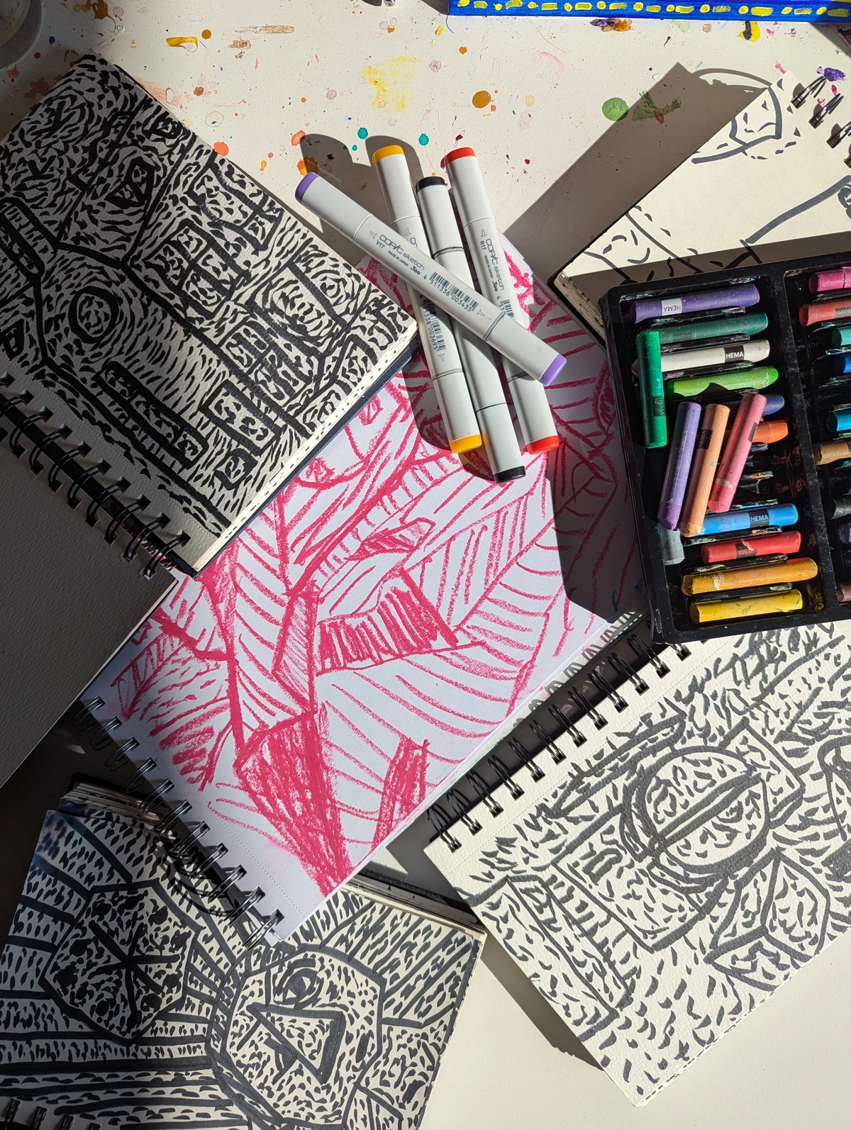 Markers and sketches on a table with paint spots