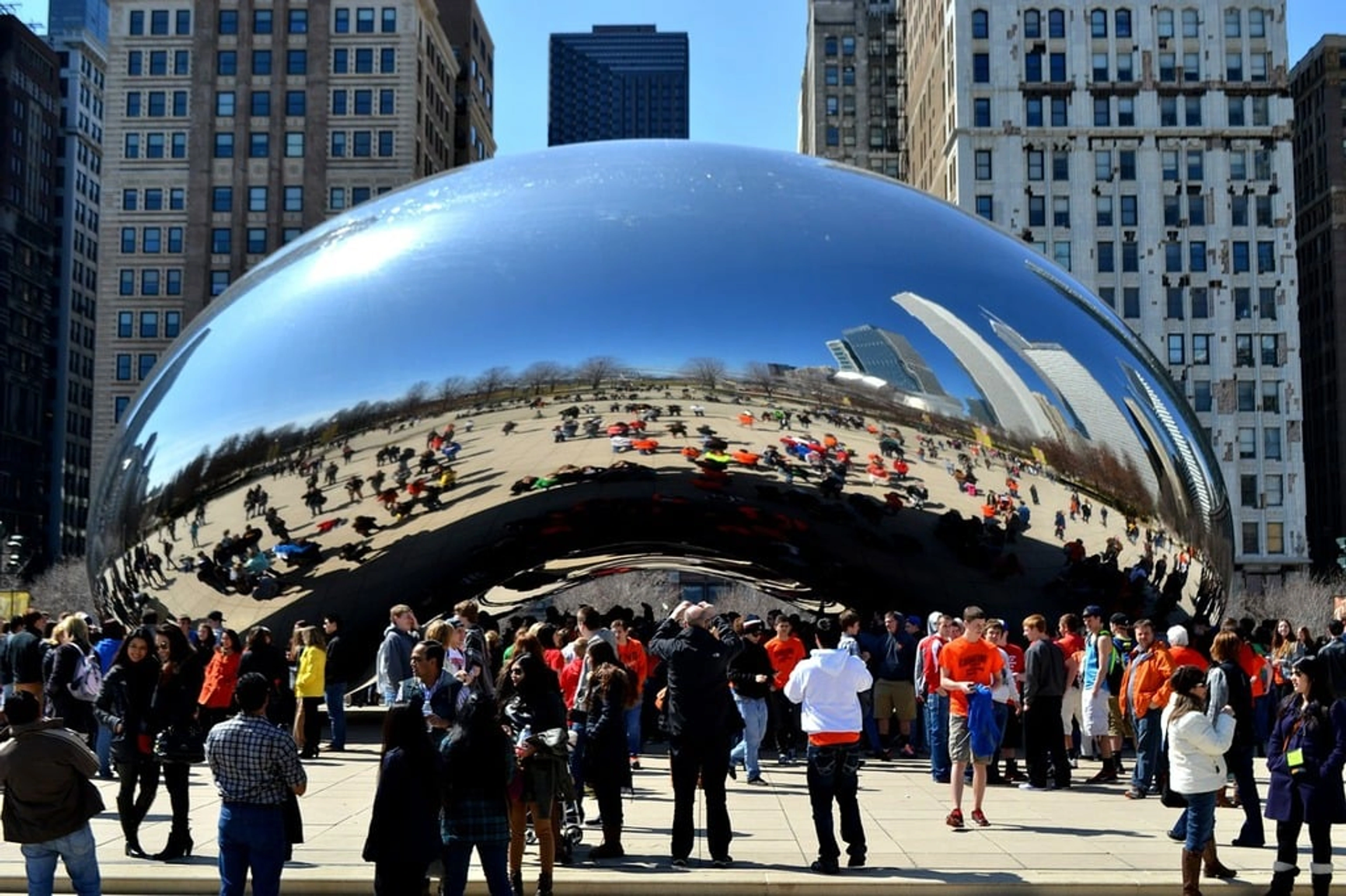 The iconic Cloud Gate 'Bean' sculpture reflecting the Chicago skyline and visitors in Millennium Park.