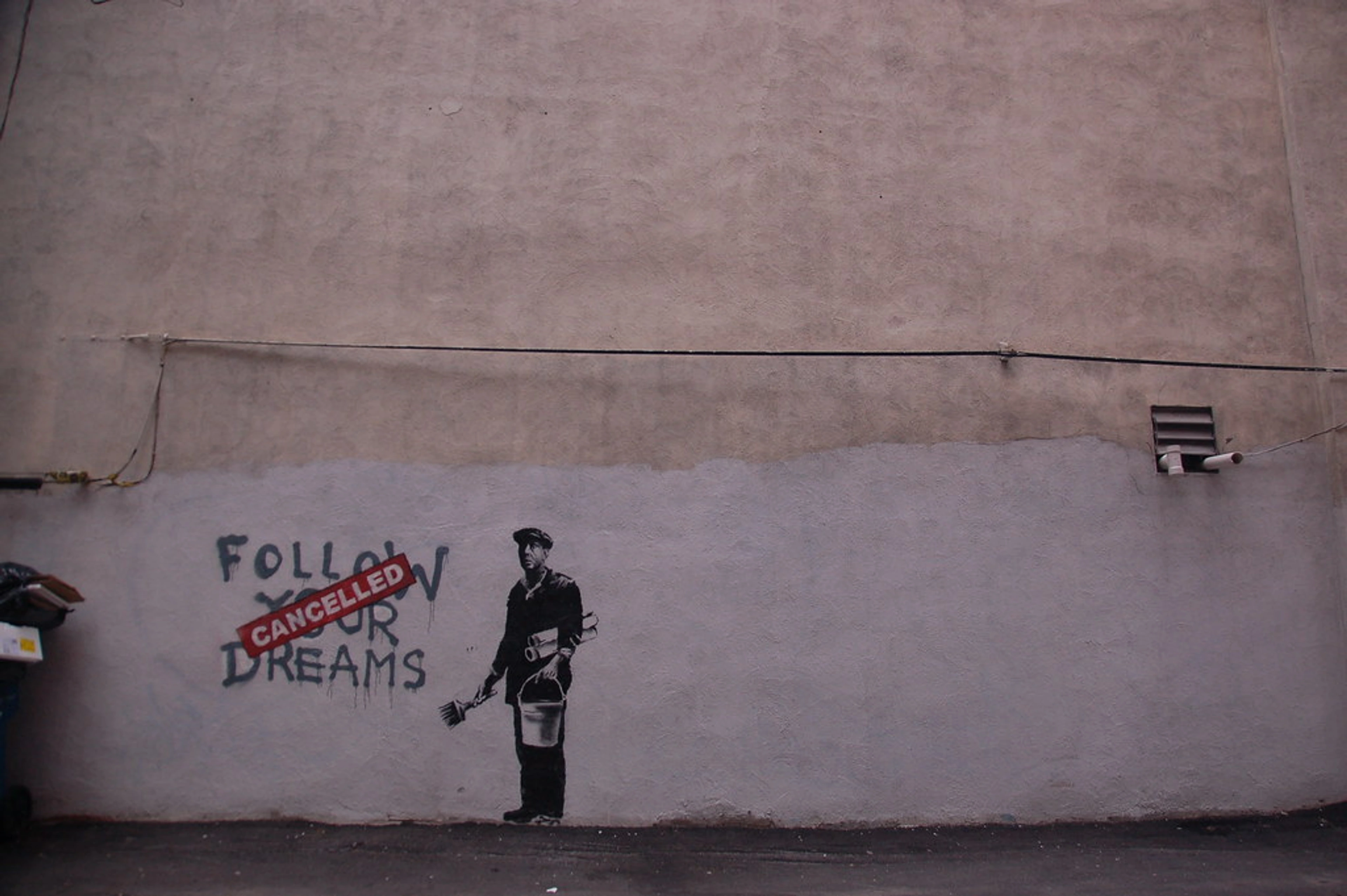 Banksy's 'Follow Your Dreams Cancelled' muurschildering in Boston, met een man die op een muur schildert.