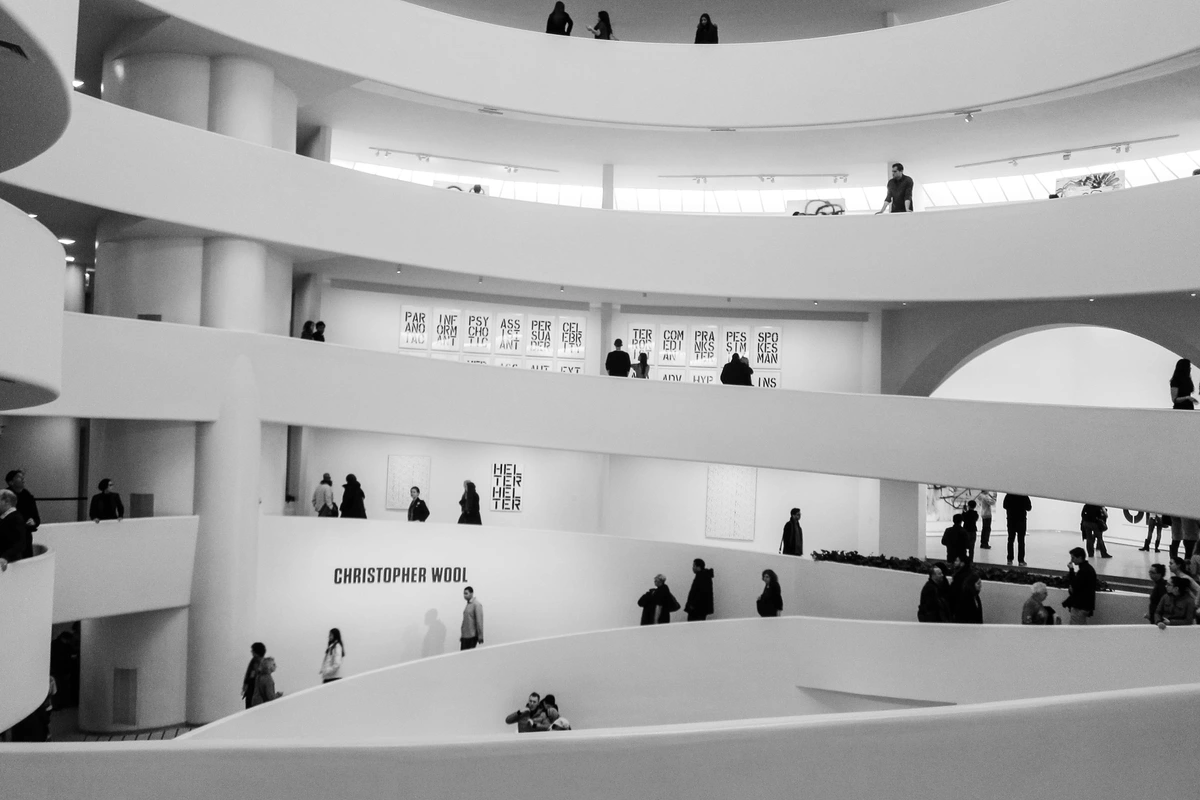 Black and white photo of the Guggenheim Museum's iconic spiral interior, with visitors walking along the ramps and viewing the Christopher Wool exhibition.