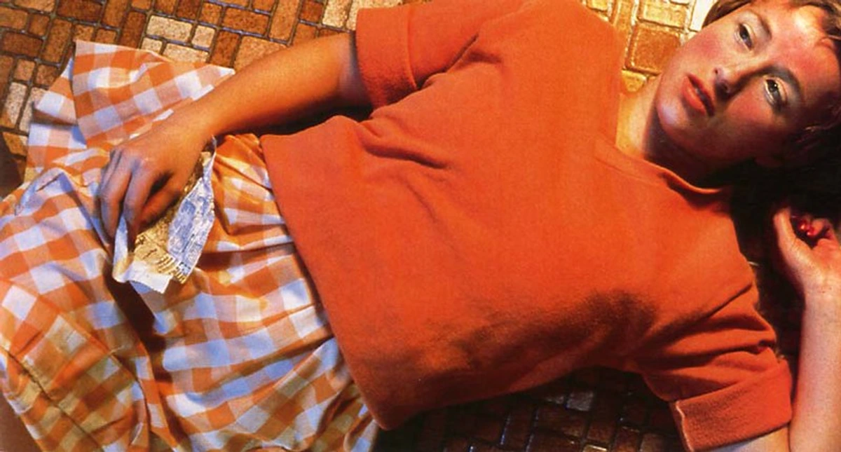 Cindy Sherman Untitled #96 self-portrait, woman in orange top and checkered skirt on tiled floor