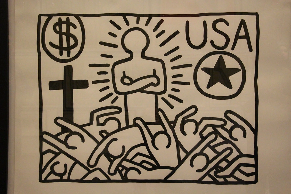 Black and white Keith Haring artwork depicting a central figure with radiating lines, a dollar sign, a cross, 'USA', a star, and a crowd of reaching hands, symbolizing political and social themes.