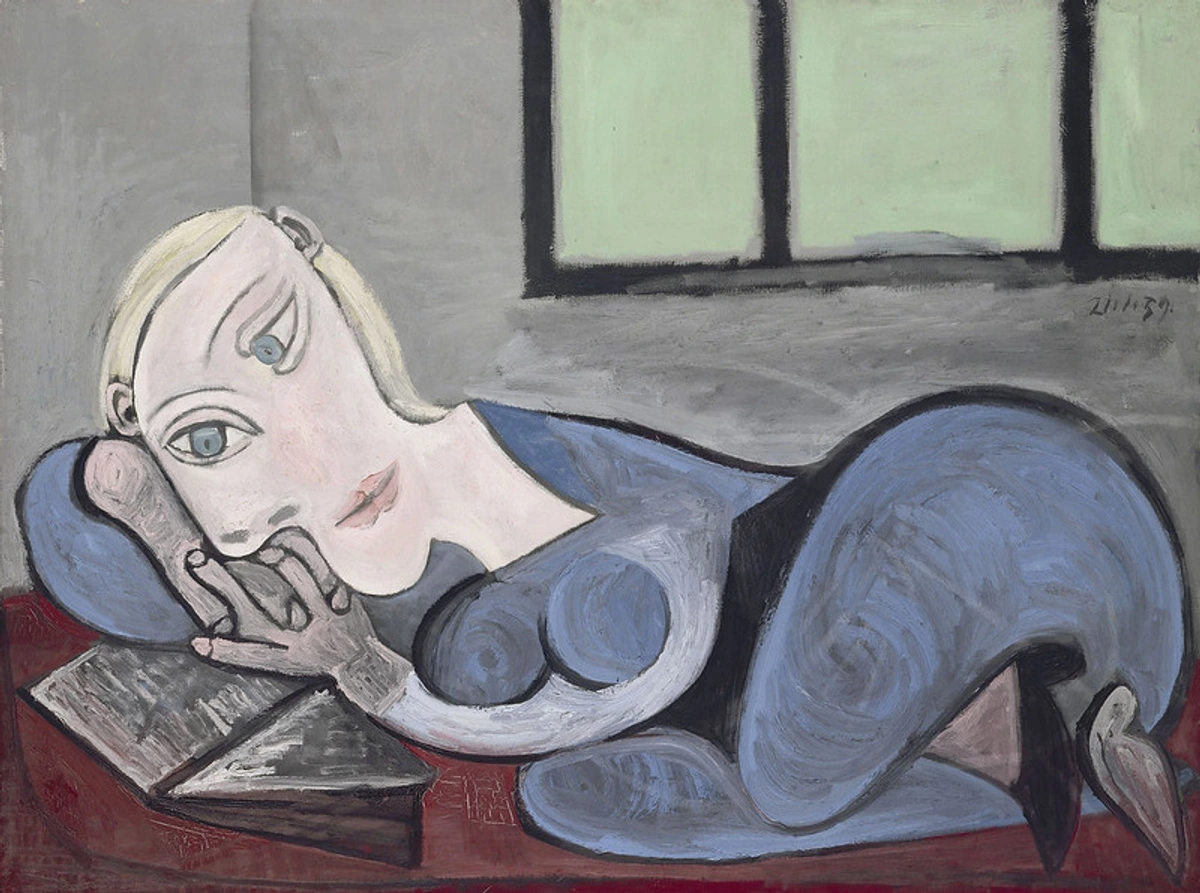 Painting by Pablo Picasso depicting a reclining woman with blonde hair reading a book, rendered in his distinct style with distorted features and muted colors.