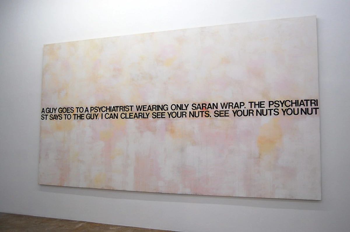 Large white painting with the text of a joke written in black letters across the center.