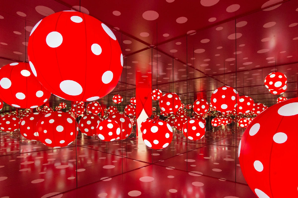 Yayoi Kusama's 'Dots Obsession' immersive art installation featuring numerous red polka-dotted spheres in a mirrored room.