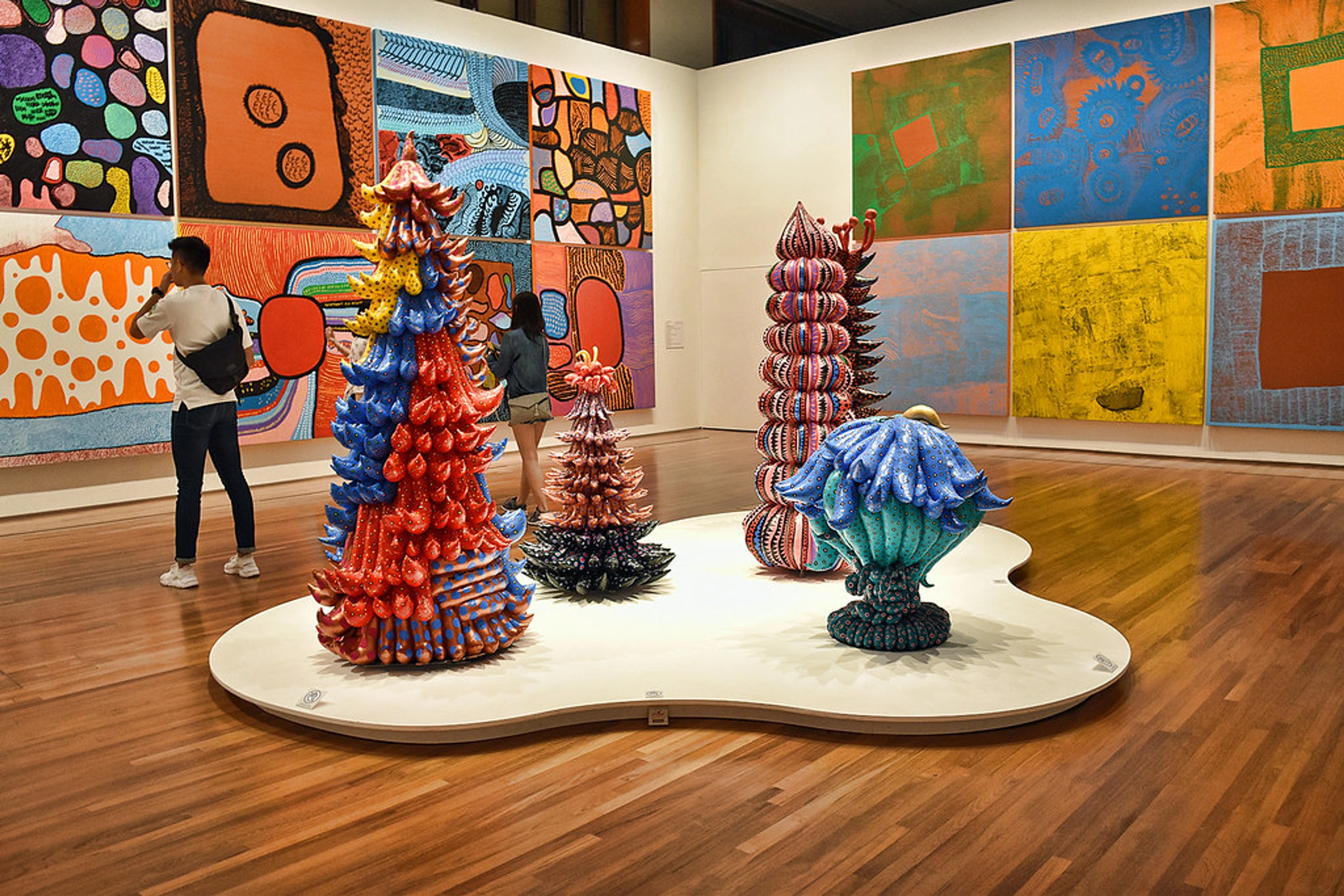 Yayoi Kusama art exhibition with colorful, organic sculptures and abstract paintings in a museum.