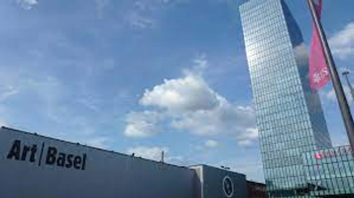 Art Basel exhibition hall and Messe Tower in Basel, Switzerland, under a blue sky with clouds