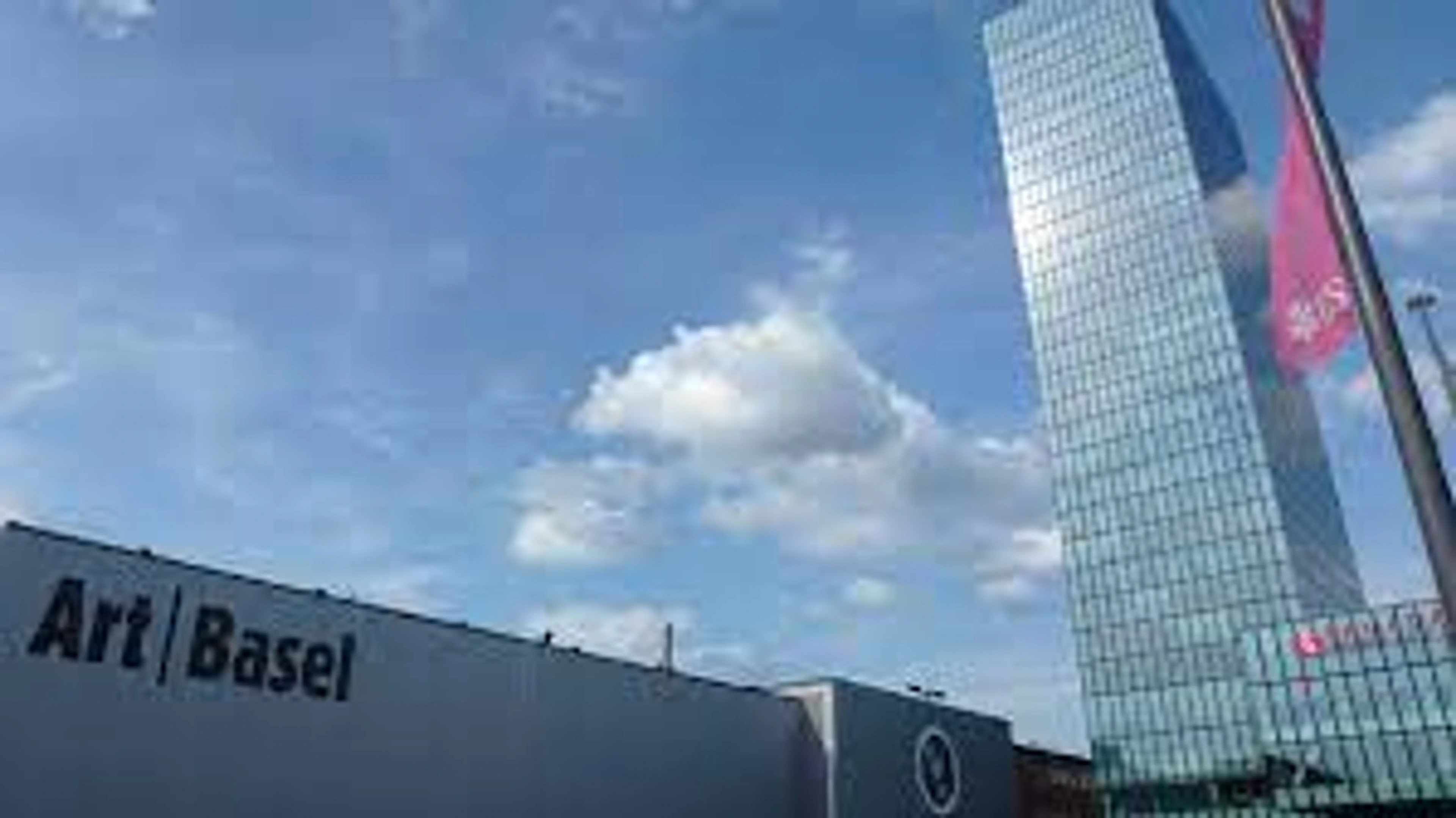 Art Basel exhibition hall and Messe Tower in Basel, Switzerland, under a blue sky with clouds