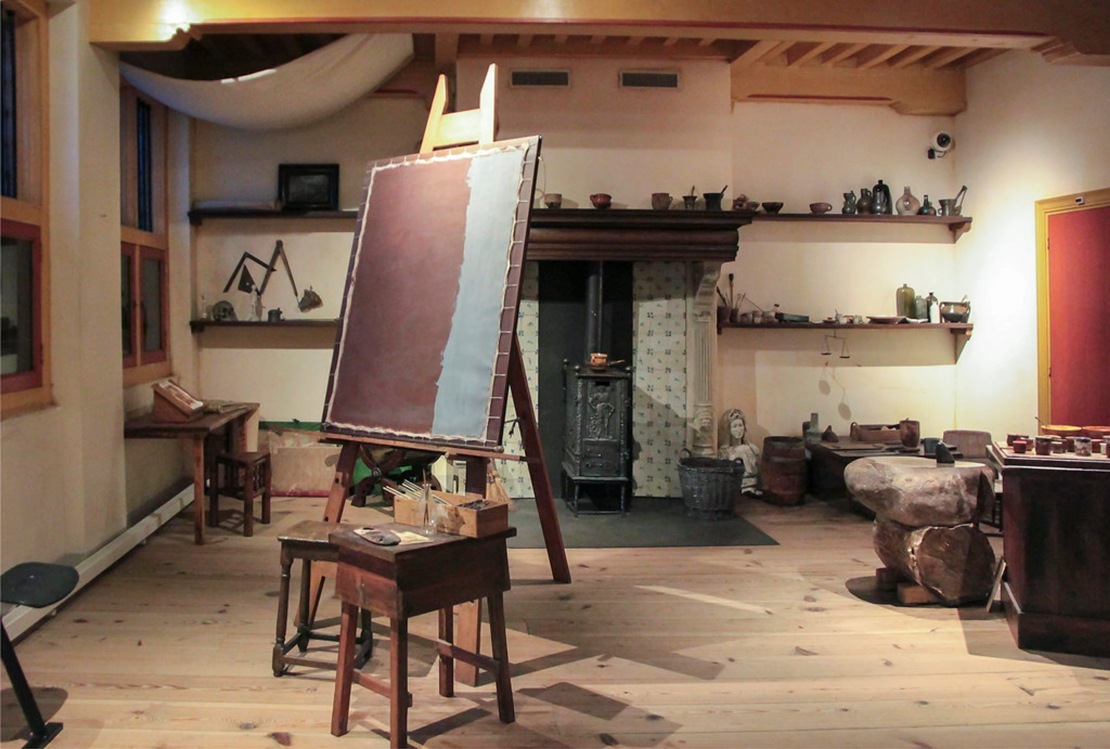 Rembrandt's recreated 17th-century artist studio at the Rembrandt House Museum, featuring an easel, fireplace, and historical art tools.