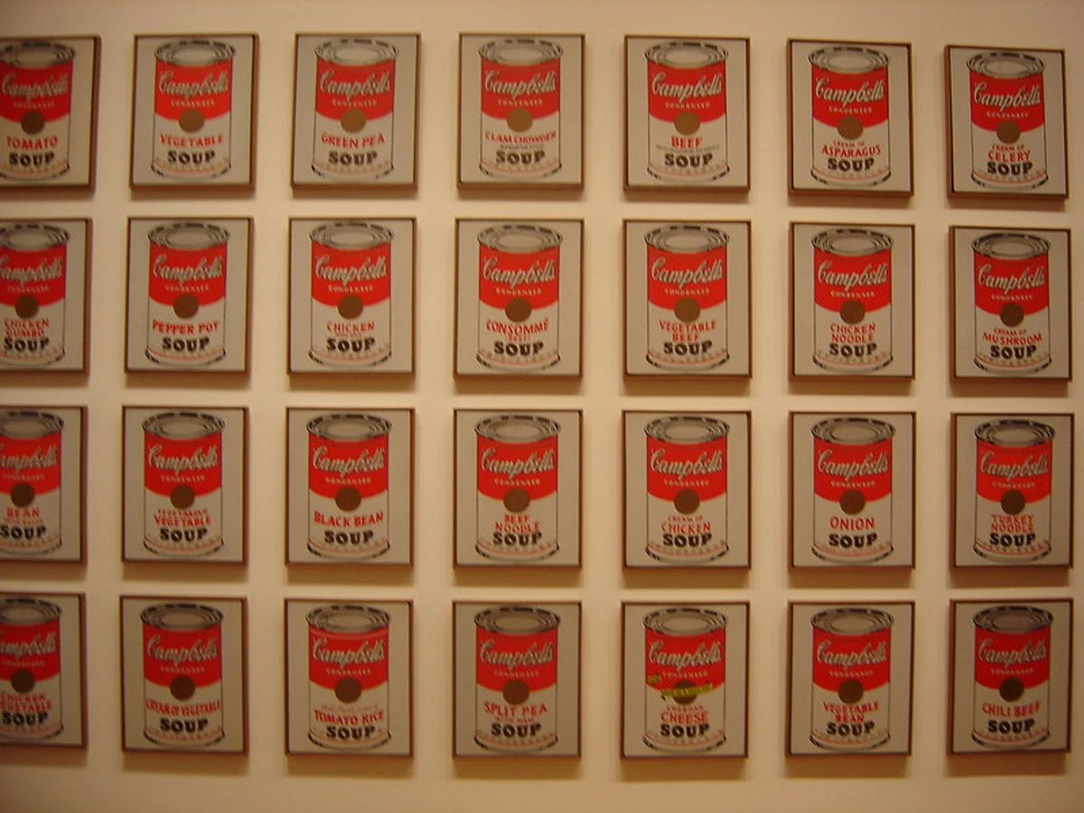 Grid van zeefdrukken van Andy Warhol met tweeëndertig verschillende soorten Campbell's soepblikken, elk afgebeeld in een eenvoudige, iconische stijl.