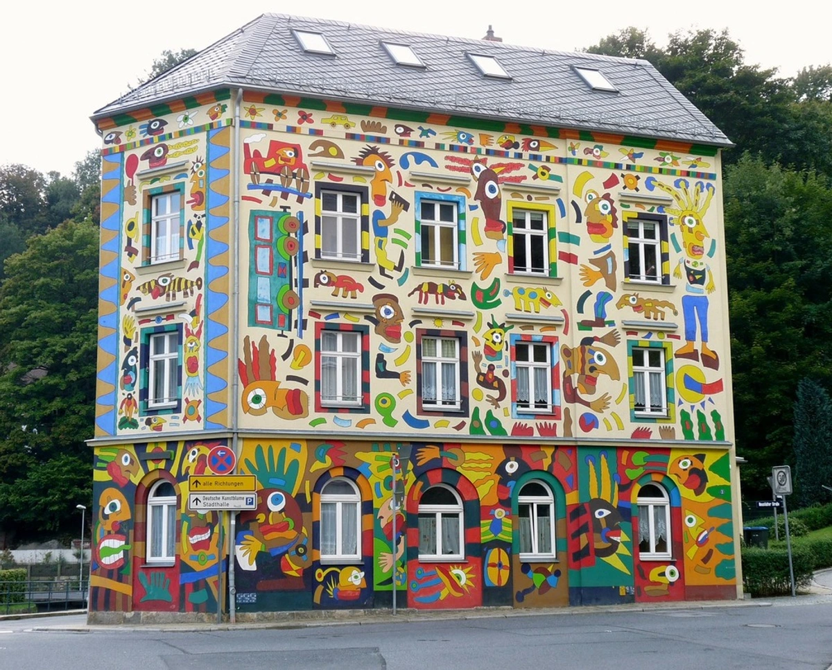 The Fischer Art House in Sebnitz, a building with its facade entirely covered in colorful, whimsical folk art paintings.