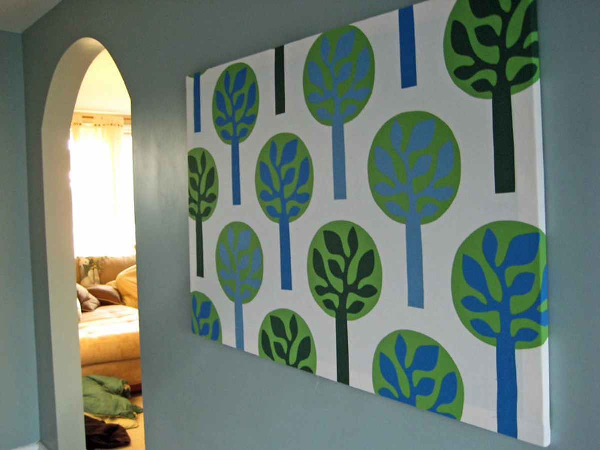 Large piece of IKEA Fredrika fabric with a stylized tree pattern in blue and green, stretched and hung as wall art in a hallway.
