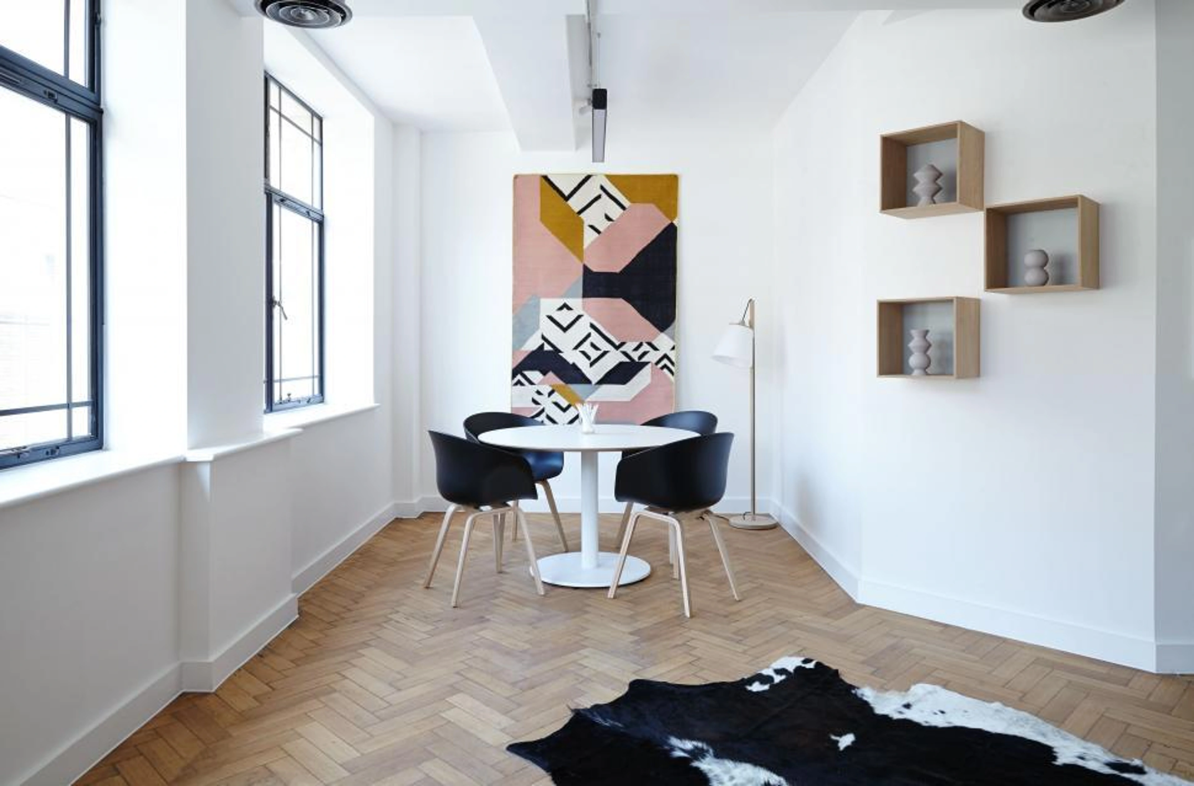 Modern dining area with vibrant geometric wall art, illustrating the impact of art on spatial dynamics and corporate interiors.