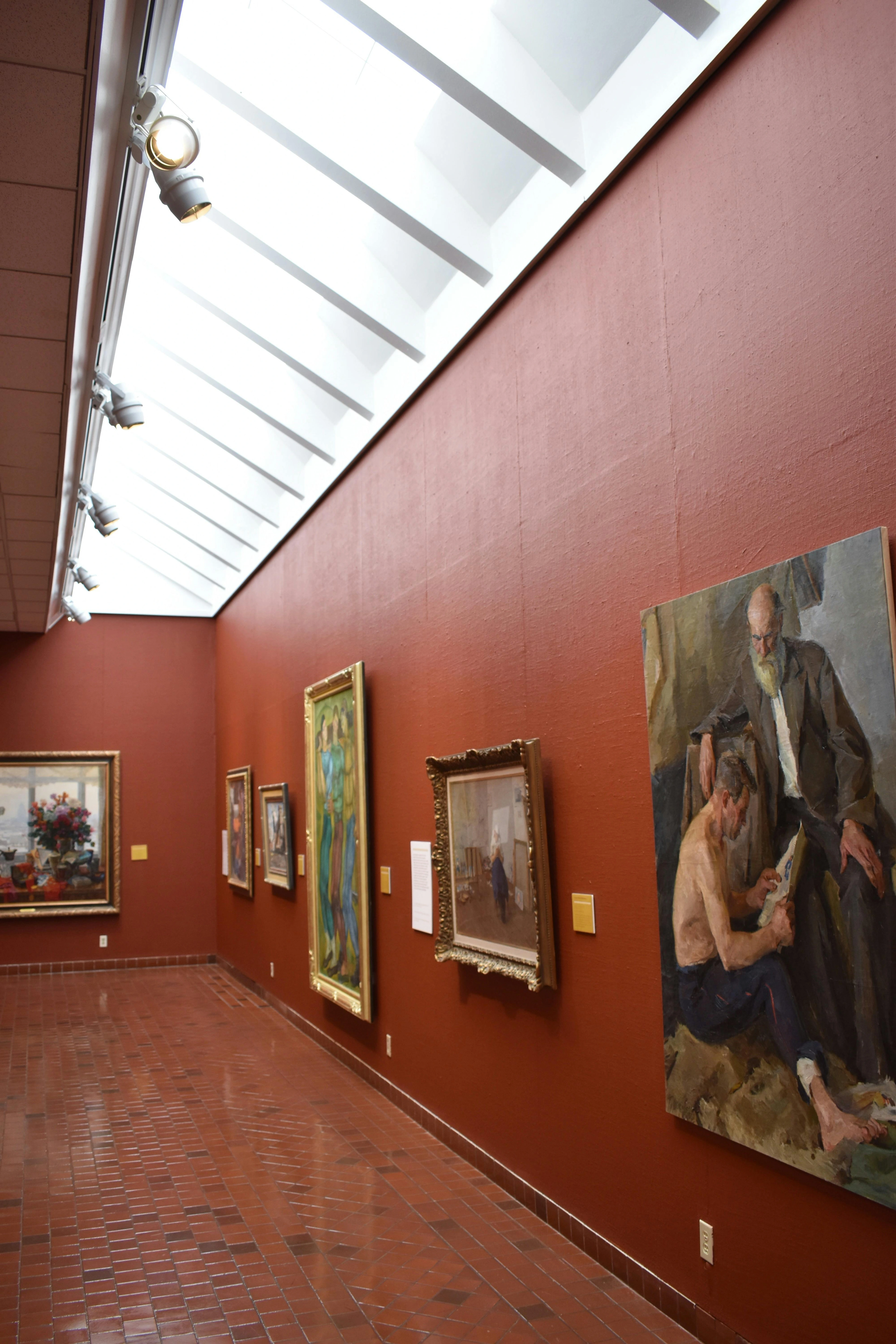 rt gallery with red walls, a skylight, track lighting, and several framed paintings displayed along the wall.