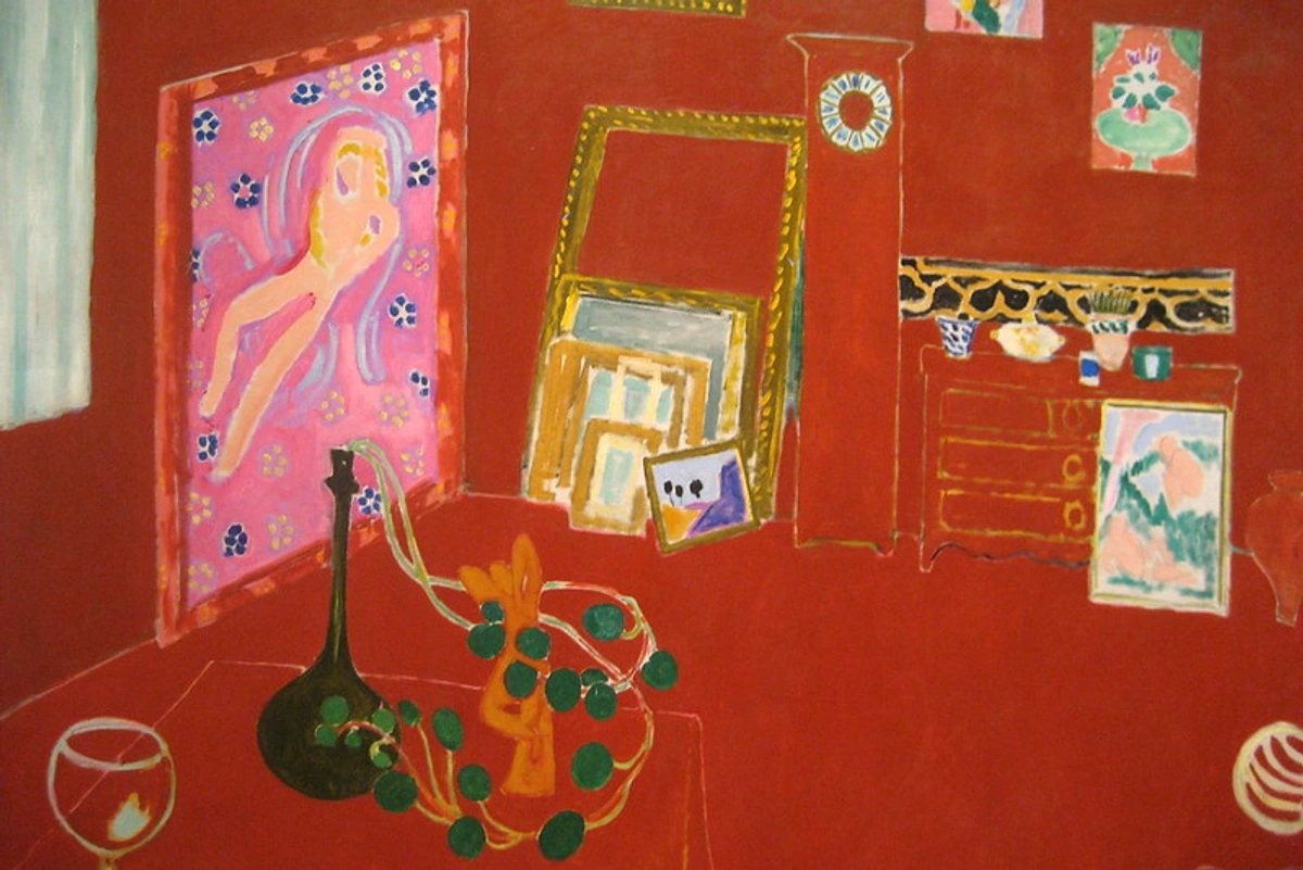 Interior view of a painter's studio rendered entirely in shades of red, featuring furniture, paintings, and objects.