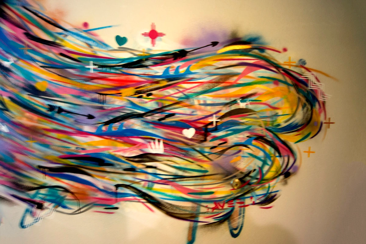 Vibrant abstract artwork with colorful swirling lines and symbolic elements like hearts, arrows, and crosses, titled "Winds of Change" by Jay Smiley.