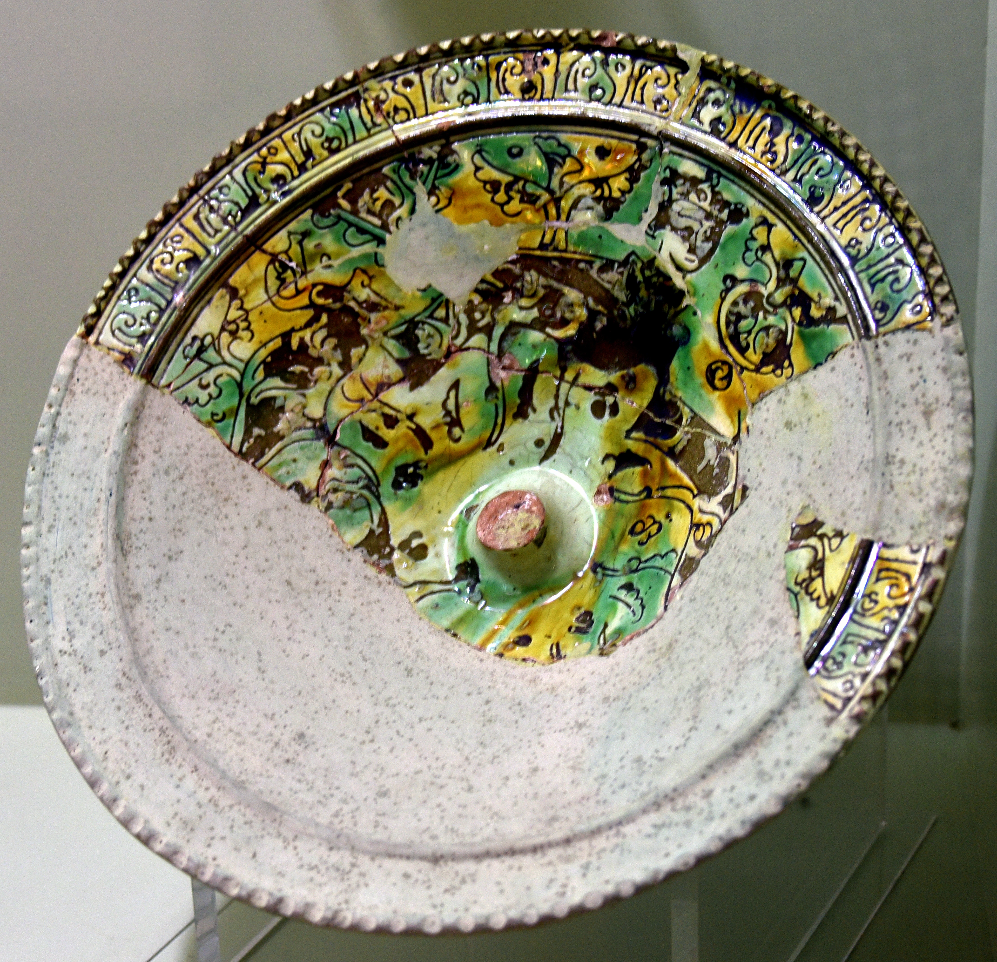 Multi-colored glazed plate in sgraffito technique, Anatolian, showing intricate patterns and some damage.